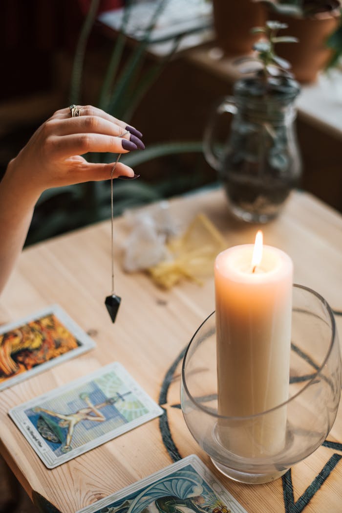 our-mission-01 A serene tarot reading setup with a pendulum and glowing candle for divination and mindfulness.