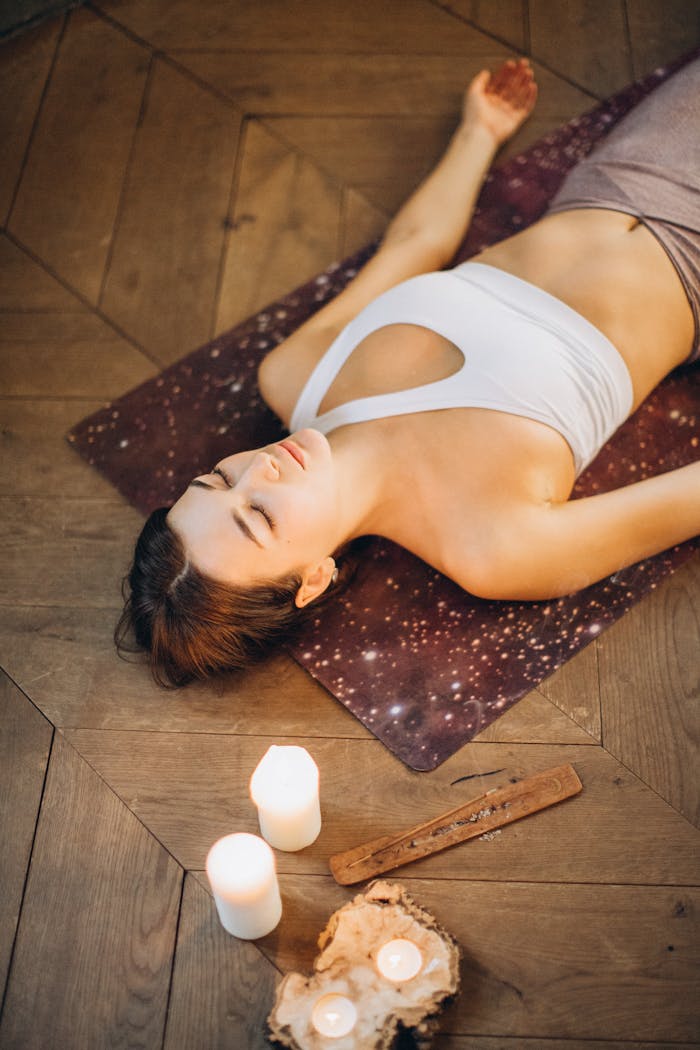 faq-img Woman practicing relaxation yoga with candles set for a calming atmosphere.